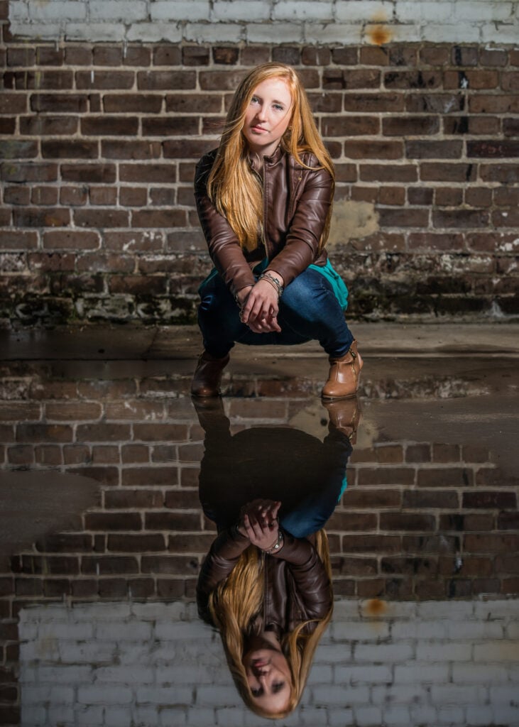 Person squatting by a reflective puddle.