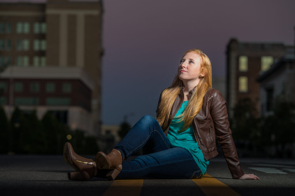 Person sitting on street at dusk.